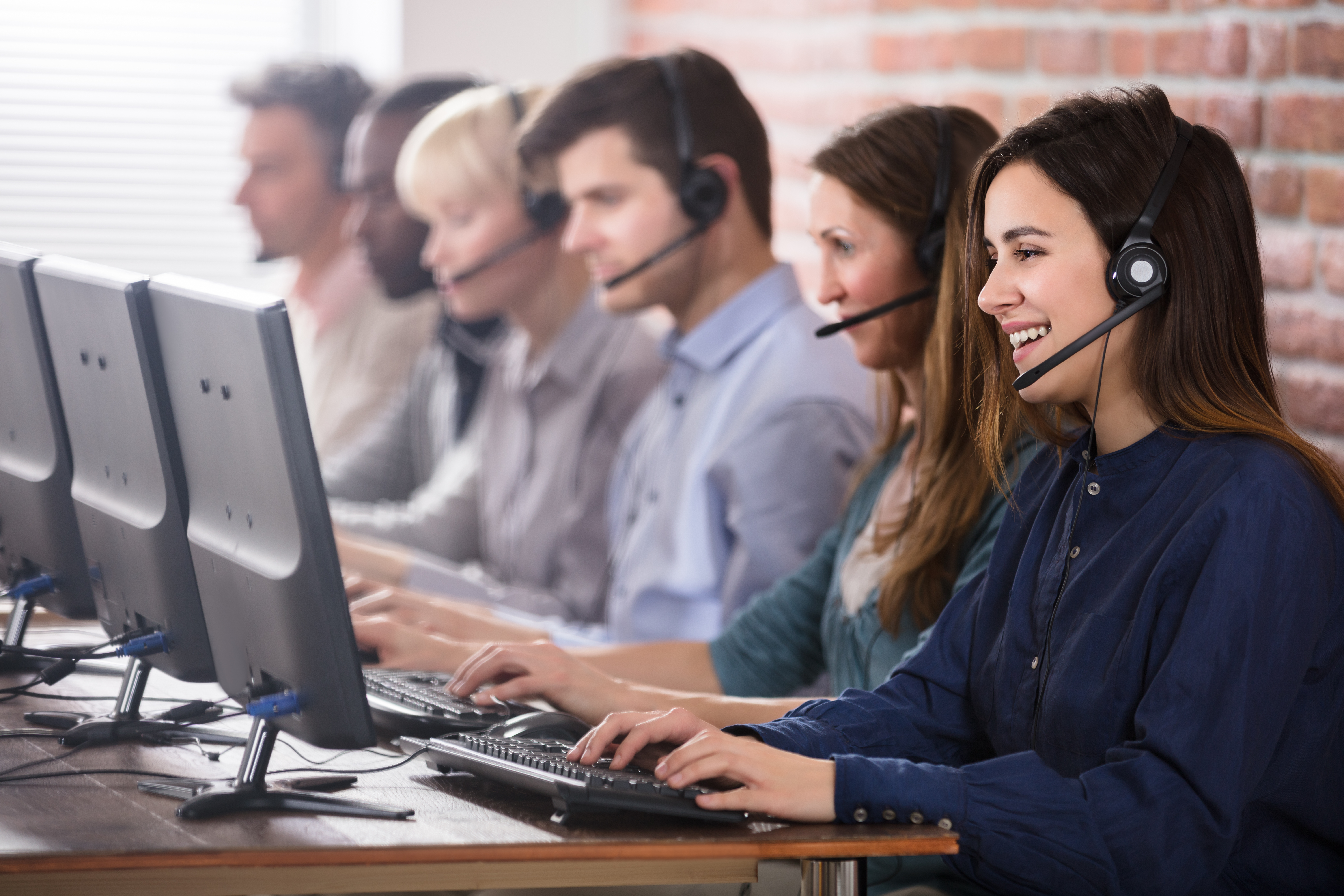 Customer service agents with headsets sitting in front of their computers in a row