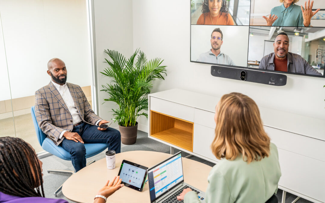 Small meeting room set up with one screen, employees and a virtual meeting going on